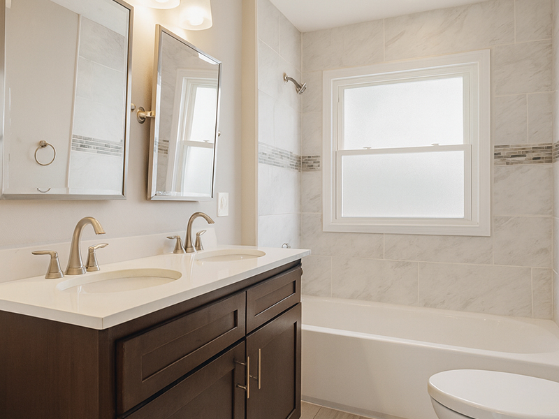 Renovated bathroom with double vanity and tile shower