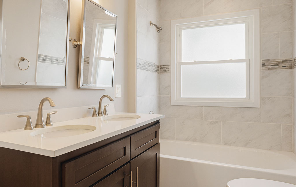 Bathroom remodeling in a Denver home featuring updated fixtures, wood vanity, and subway tile shower